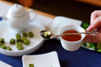 Midsection of person holding tea cup on table
