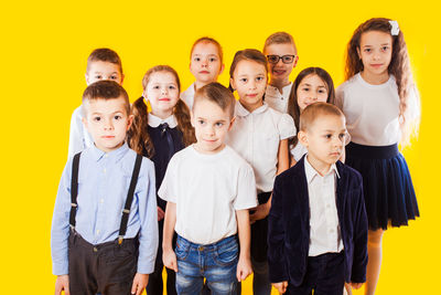 Portrait of friends standing against yellow background