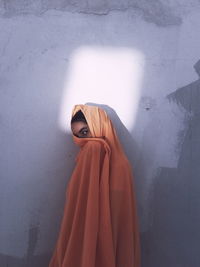 Portrait of woman standing against wall covered with shadow