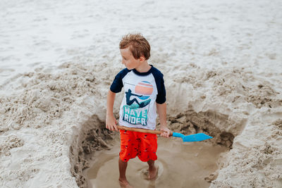 High angle view of boy digging sand at beach