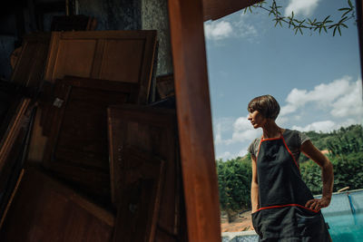 Portrait of a female craftsperson and a pile of old wooden panels