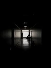 Silhouette person walking in illuminated corridor