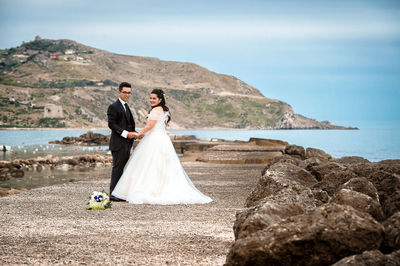 Couple standing on beach by sea against sky