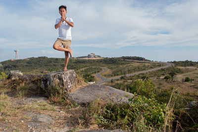 Woman standing on rock by land against sky
