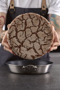 Hands holding rye sourdough bread over cooking pan