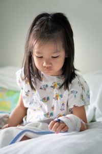 Close-up of cute girl sitting on hospital bed