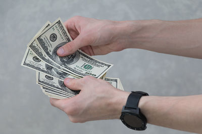 Cropped hands counting paper currencies against wall