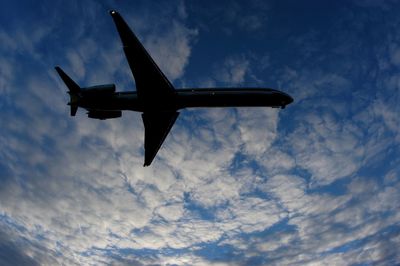Low angle view of airplane against cloudy sky