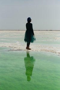 Rear view of woman standing at beach