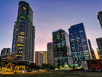 Illuminated buildings in city against sky at dusk