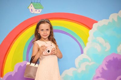 Portrait of girl standing against paint