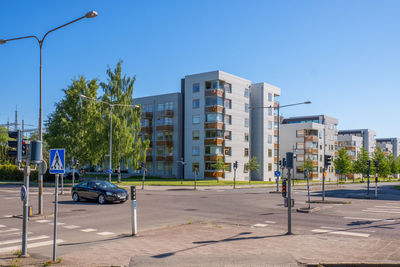 Cars on road by buildings against blue sky