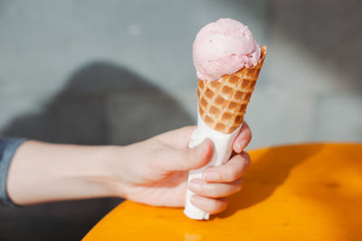 Close-up of woman holding gelato ice cream cone over table