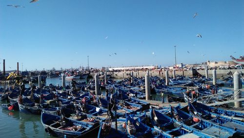 Boats moored in harbor against clear blue sky