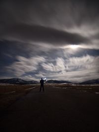 Full length of man standing on land against cloudy sky