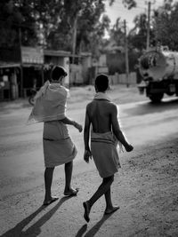 Rear view of people walking on road