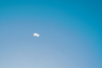 Flying empty white plastic bag in front of blue sky