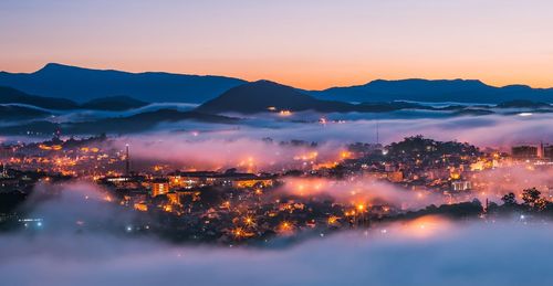 Illuminated city against sky during sunset
