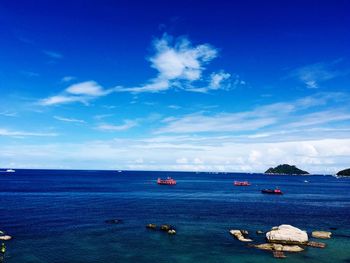 Boats sailing in sea against blue sky