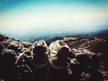 High angle view of shoes on rock against sky