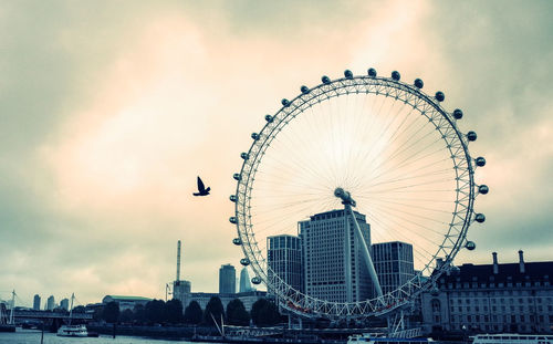 Ferris wheel in city against sky during sunset
