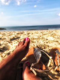 Low section of person on beach against sky