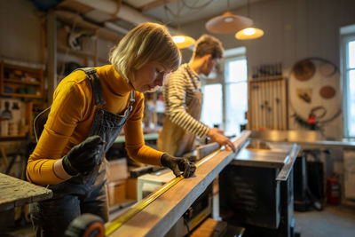 Side view of woman using mobile phone while standing in factory