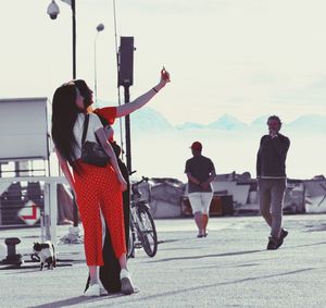 Rear view of people walking on road against sky