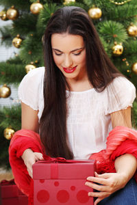 Beautiful young woman with red christmas tree in box