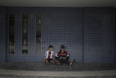 People sitting by ball on wall at night