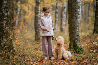 Side view of woman with dog standing in forest