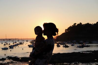 Couple on beach against sky during sunset