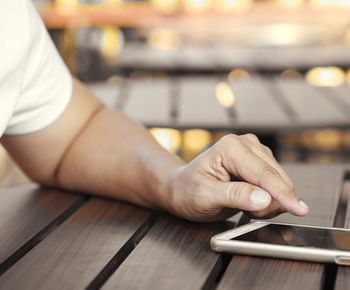 Close-up of man using mobile phone on table