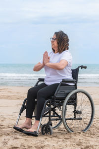 Woman sitting on wheelchair at beach