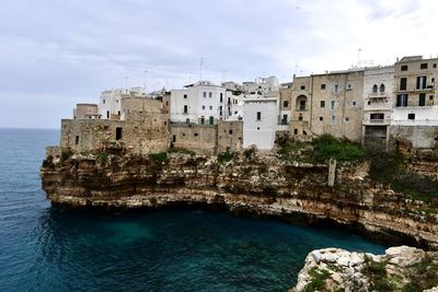 Buildings by sea against sky