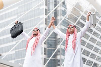 Businessmen in traditional clothing standing against skyscraper