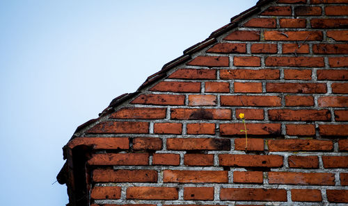 Low angle view of brick wall by building against sky