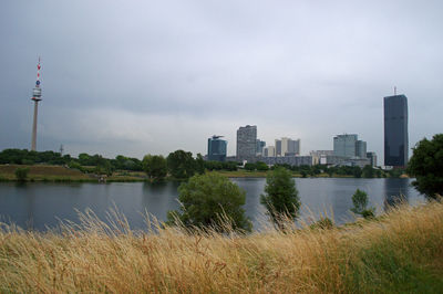 Scenic view of river by buildings against sky