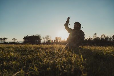 Rear view of man standing on field against clear sky
