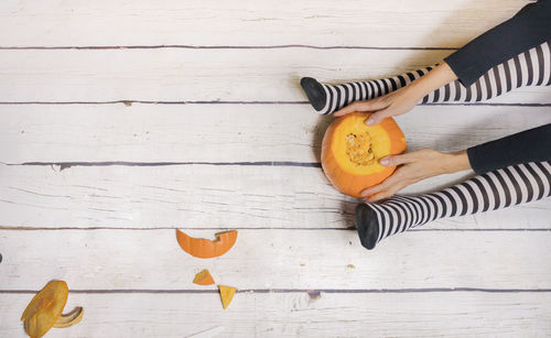 High angle view of hand holding orange on table