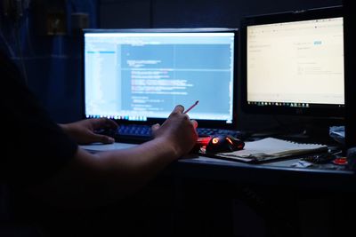 Man holding cigarette while using computer at office