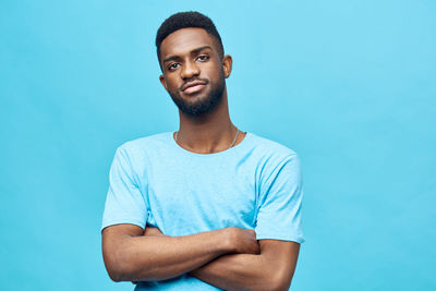 Portrait of young man standing against blue background