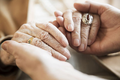 Adult daughter holding hands of her mother, close-up