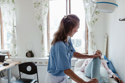 Female nurse examining patient's leg at clinic