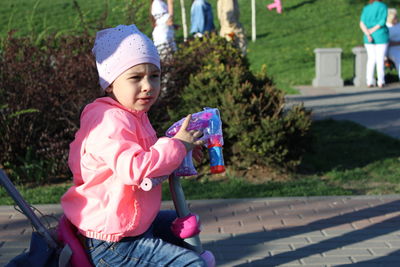 Cute girl holding pink while sitting outdoors