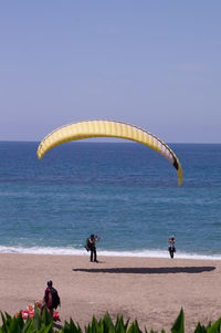 People on beach by sea against sky