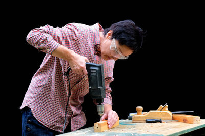 Man working on table against black background