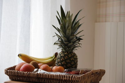 Fruits in basket on table against wall at home