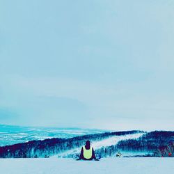 Rear view of people on snow covered land against sky