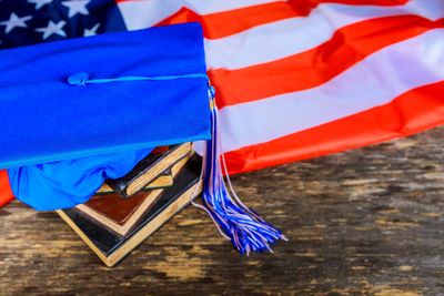 Close-up of mortarboard with books on american flag at table